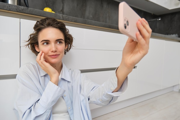 retrato mujer joven sentada suelo cocina telefono tomando selfie smartphone aplicacion 1258 187212
